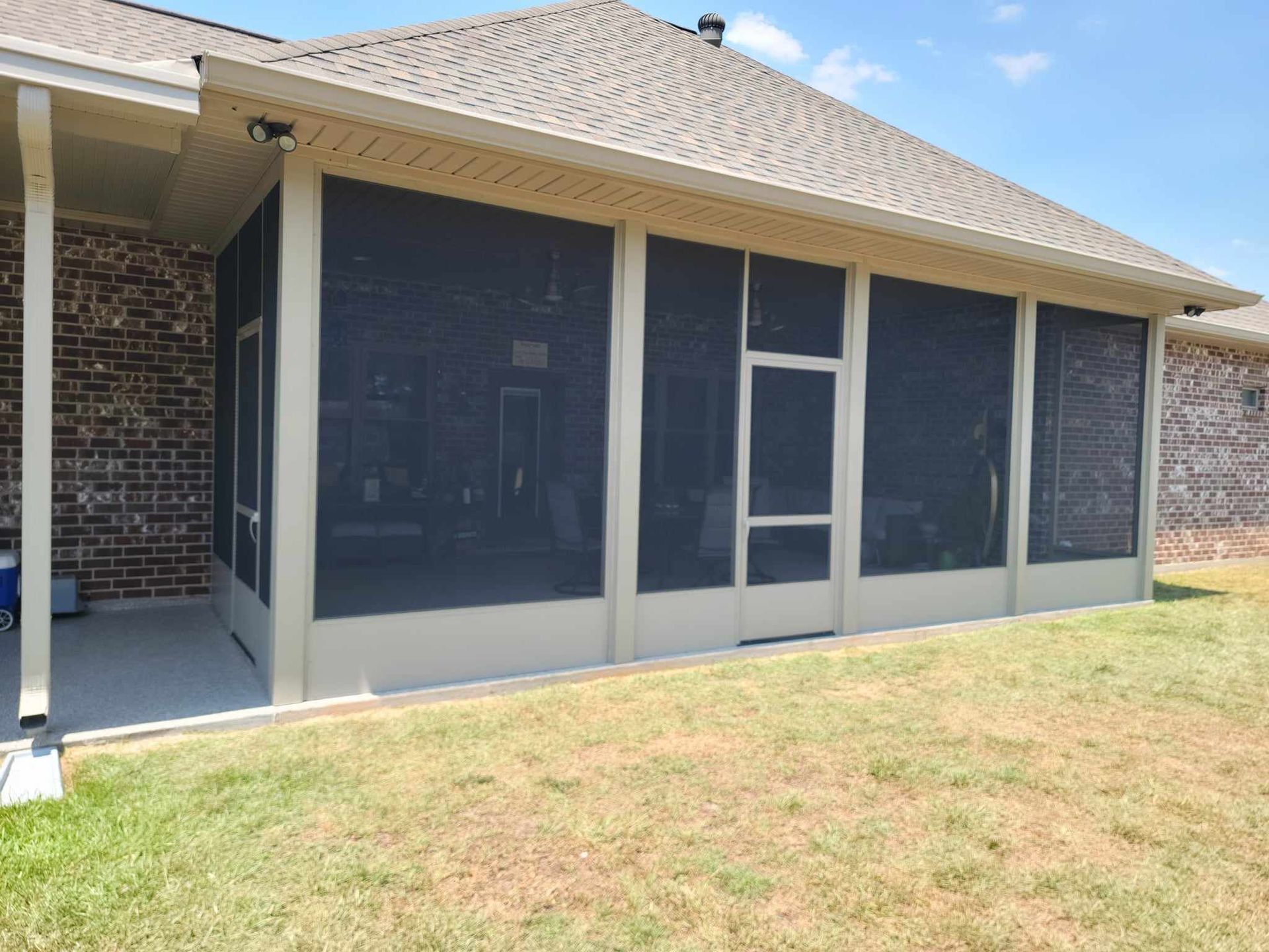 There is a screened in porch in the backyard of a house.